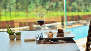 A dining table with a glass of red wine, a plate with food, and two small potted plants. - Nobile Hotel Convention Ciudad Del Este (Ciudad Del Este)
