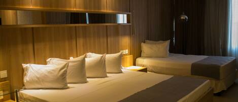 Habitación de hotel con dos camas, paneles de madera, una mesita de noche con lámpara y un espejo grande sobre las camas.