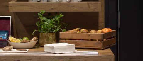 Una encimera de madera con un tazón de jengibre, una planta, un libro y una caja de frutas.
