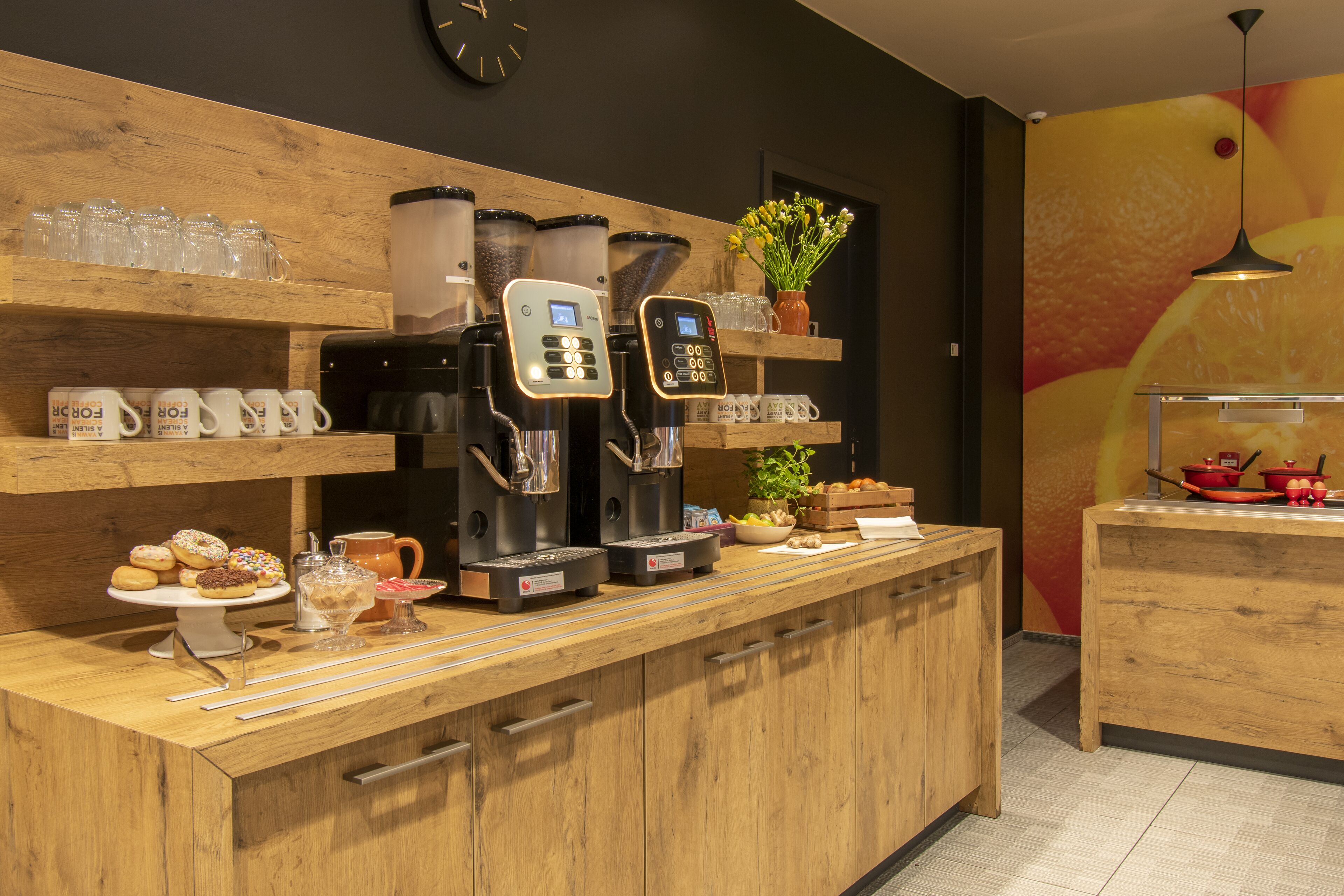 Una cocina con armarios de madera, una estación de café con varias cafeteras y una exposición de frutas.