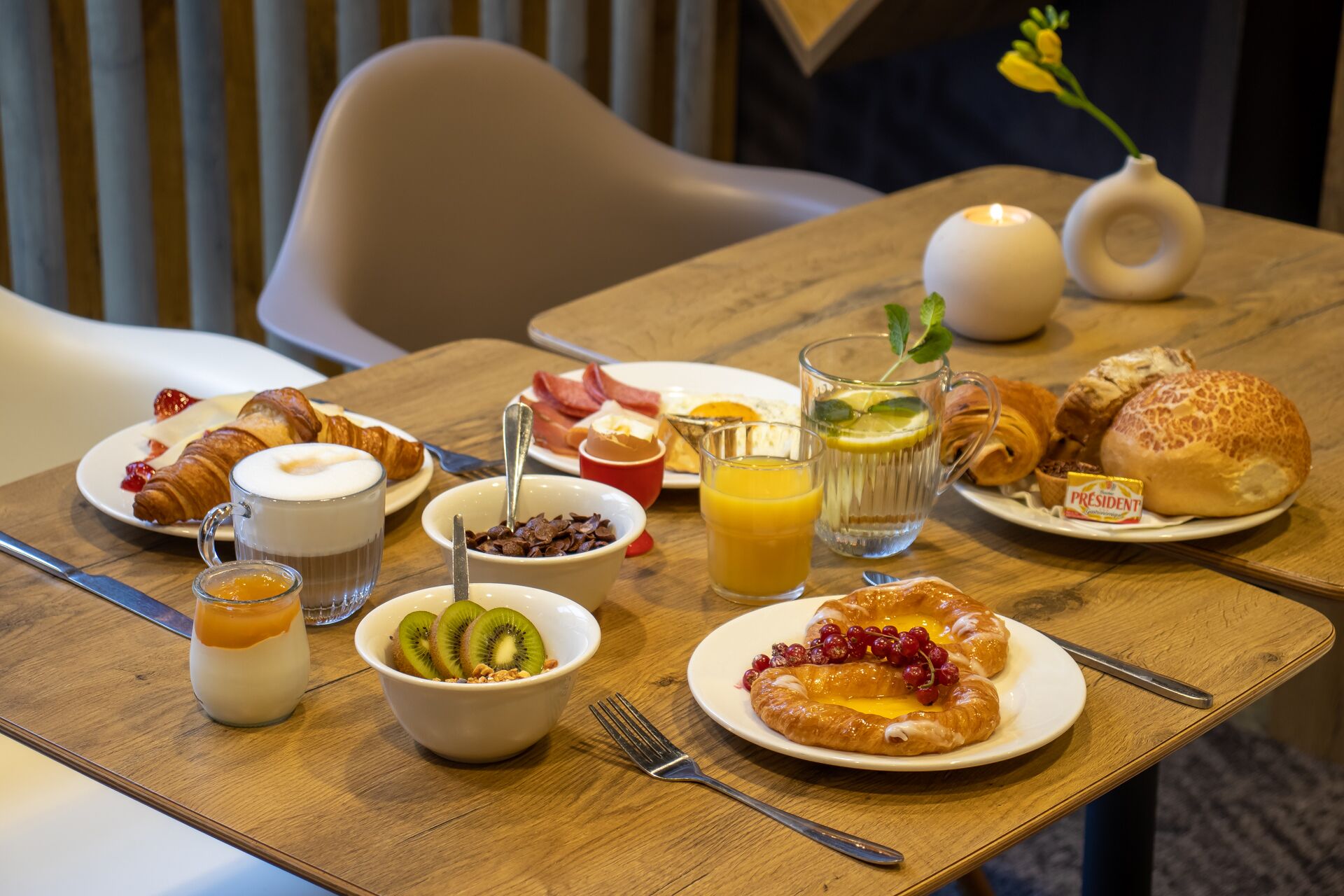 A breakfast table with croissants, fruit, and beverages.