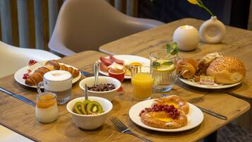 A breakfast table with croissants, fruit, and beverages.