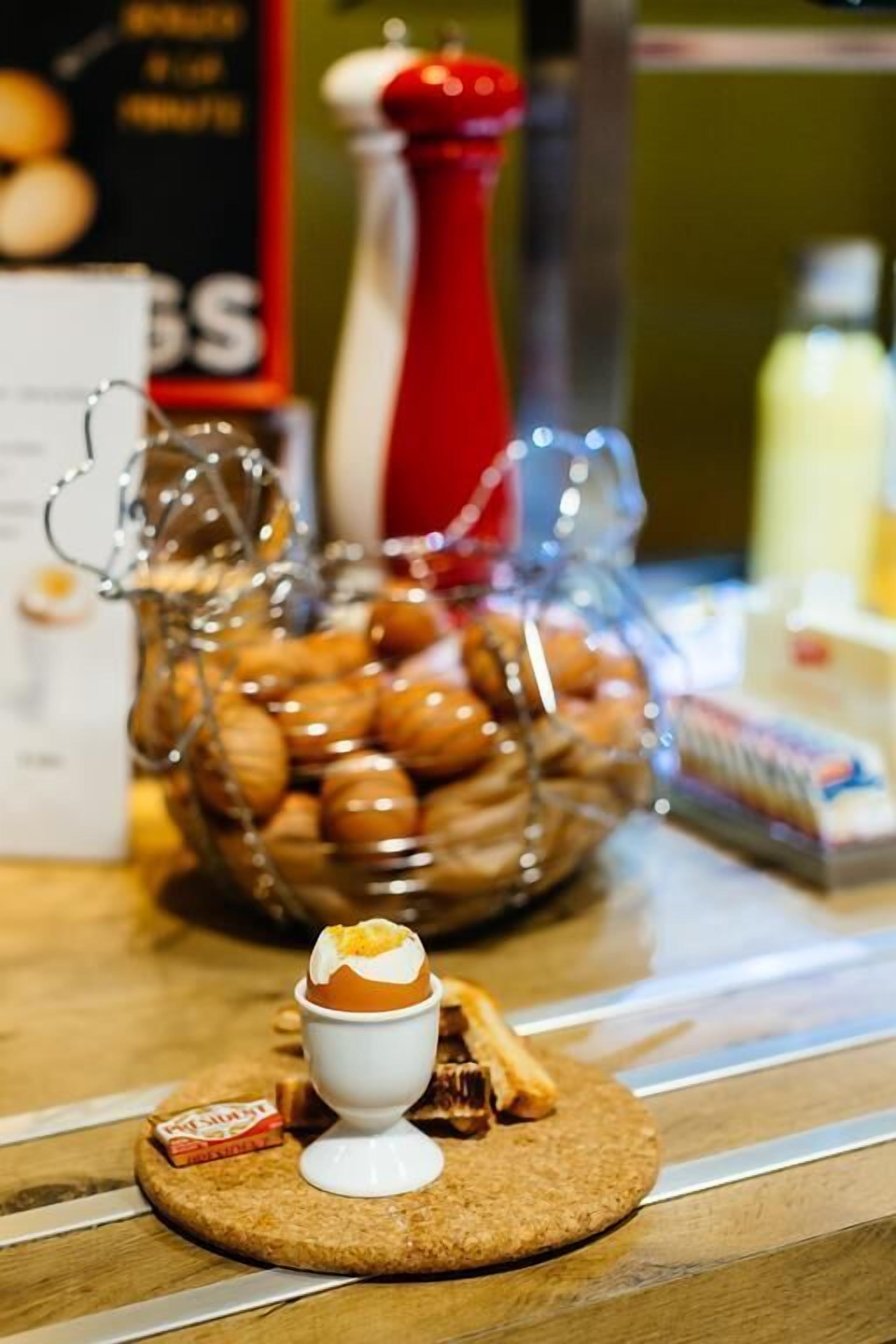 A dessert setup with a bowl of cookies, a small cup of ice cream, and a cookie on a wooden board.