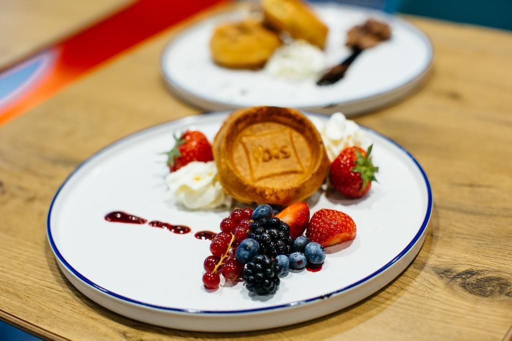A plate with a waffle, strawberries, blueberries, and a dollop of whipped cream.