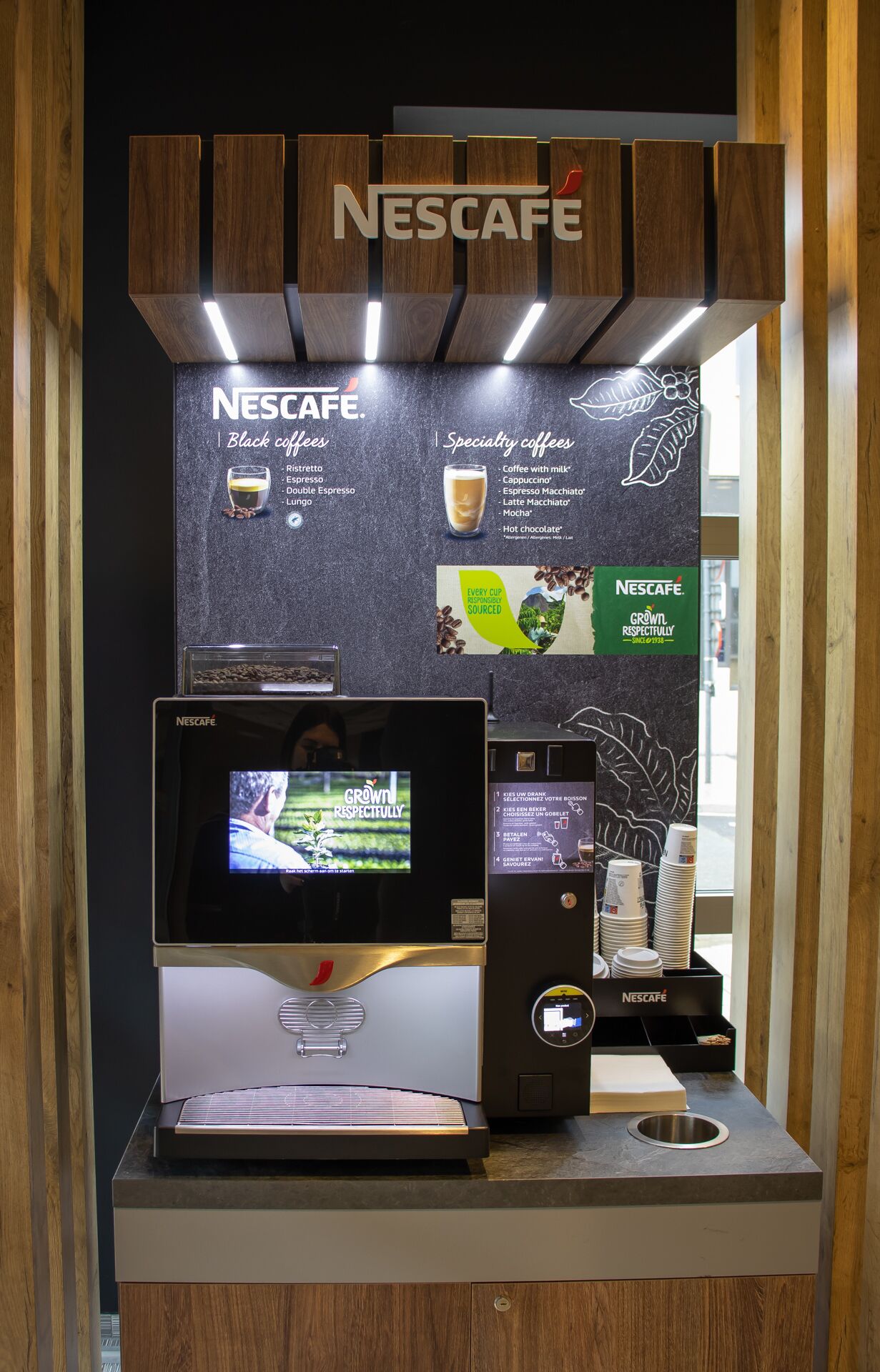 A Nescafe coffee station with a digital menu display, a coffee machine, and a coffee grinder.