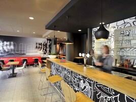A modern bar area with a counter, stools, and a bartender.