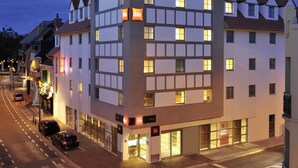 Un hôtel à plusieurs étages au design moderne, doté de grandes fenêtres et d’une enseigne « ibis » bien visible.