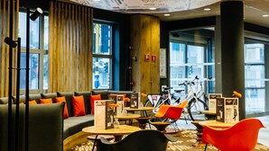 Un intérieur moderne avec un plafond de forme circulaire, un coin salon doté de coussins orange et des vélos en arrière-plan.