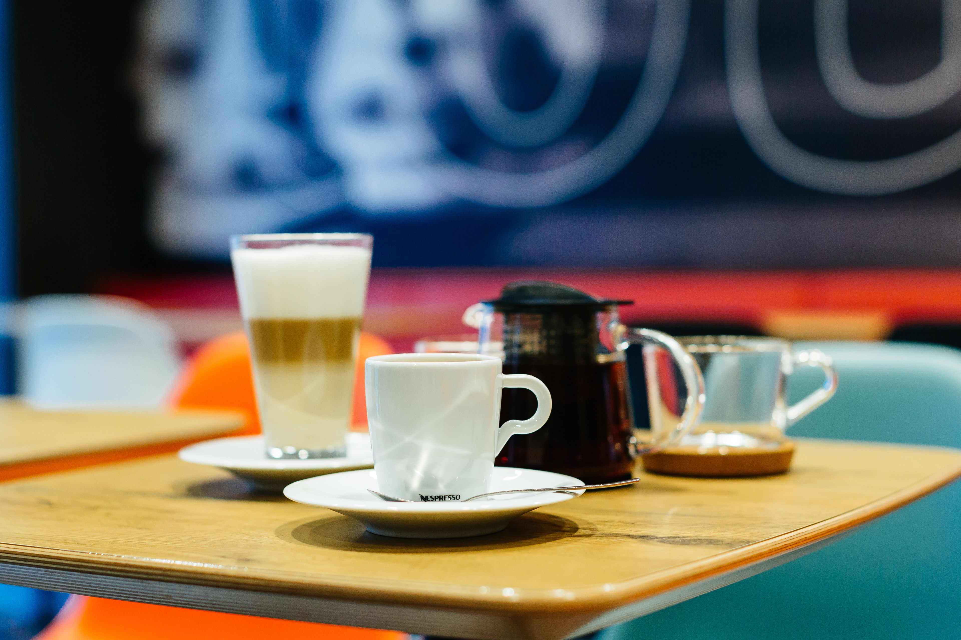 A table with a coffee pot, a cup of coffee, and a glass of milk.