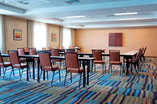 A conference room with multiple tables and chairs, a patterned carpet, and a large window with curtains. - Fairfield Inn & Suites Des Moines Urbandale (Urbandale)