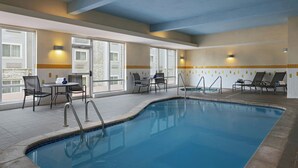 An indoor swimming pool with a tiled floor, a pool ladder, lounge chairs, and a table with chairs. - Fairfield Inn & Suites Des Moines Urbandale (Urbandale)