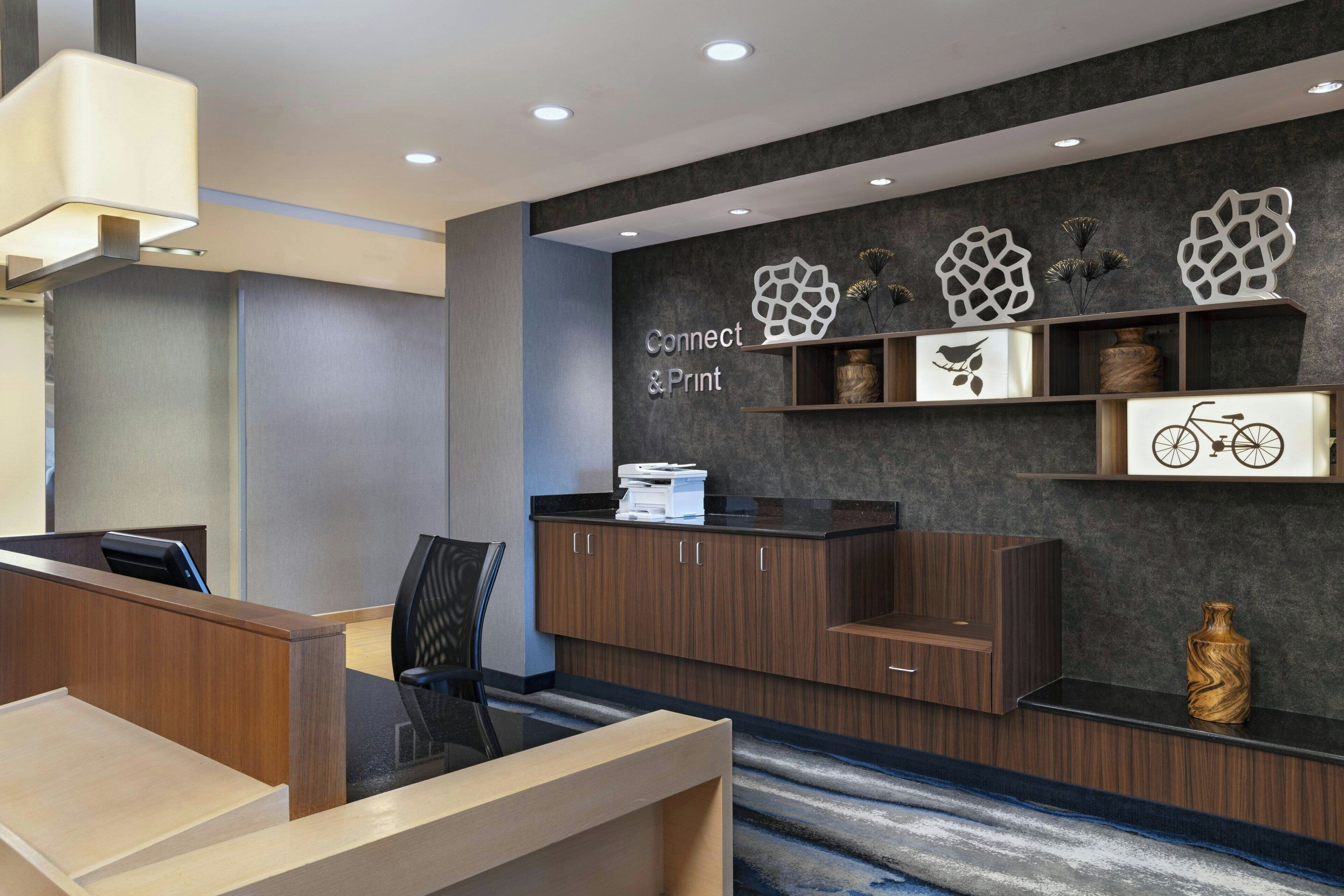 A modern reception area with a desk, chairs, and a wall-mounted sign reading 'Connect & Print'.