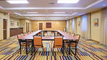 A conference room with a long table, chairs, and a carpeted floor.