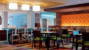 A modern hotel lobby with a reception desk, multiple seating areas with chairs, and a colorful carpet. - Fairfield Inn & Suites Des Moines Urbandale (Urbandale)