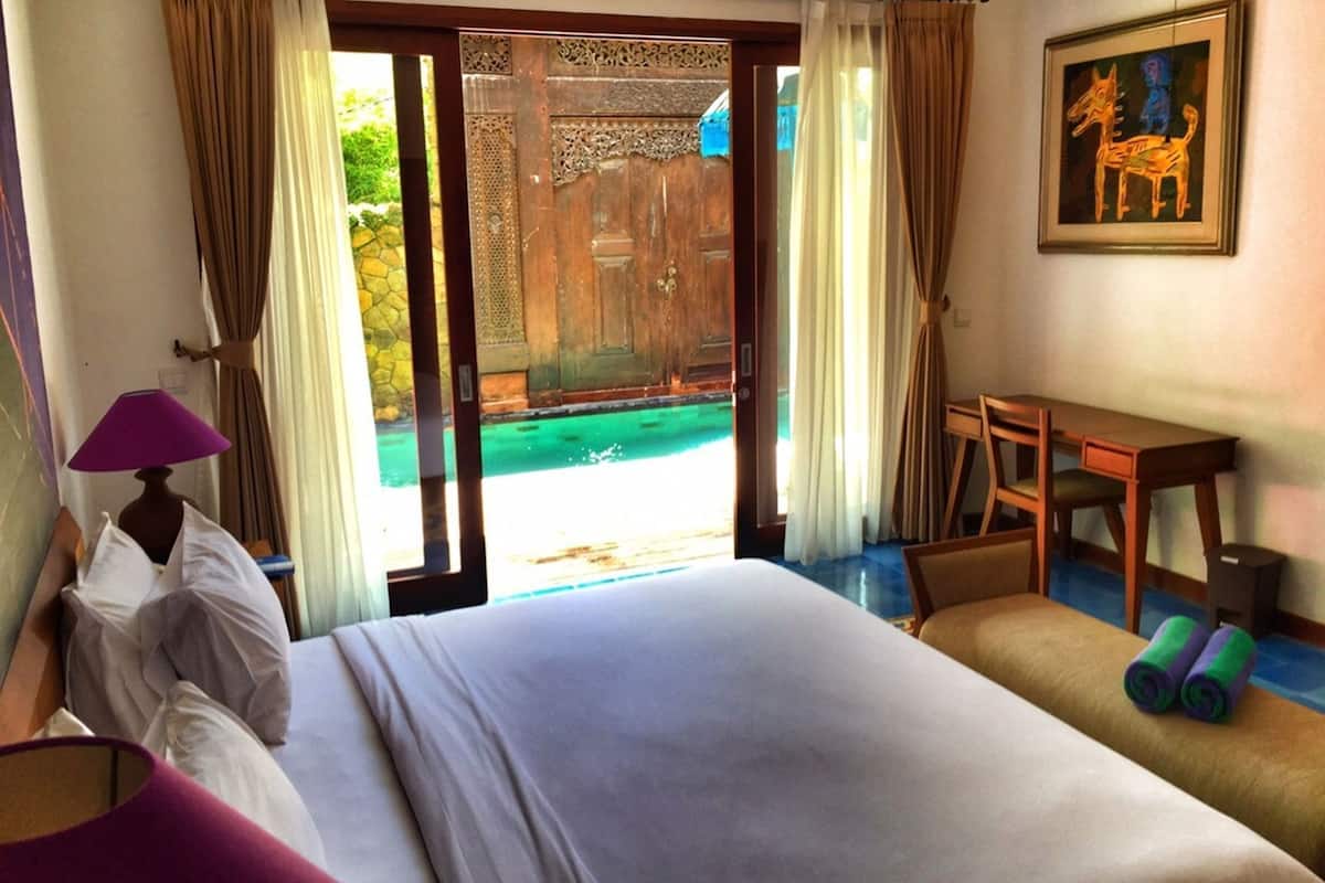 Una habitación de hotel con una cama, un escritorio, una silla, una lámpara y un cuadro en la pared.