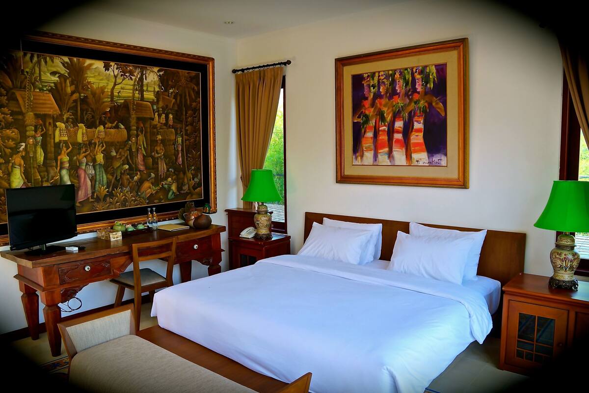 Una habitación de hotel con una cama grande, un escritorio con televisor y dos lámparas.