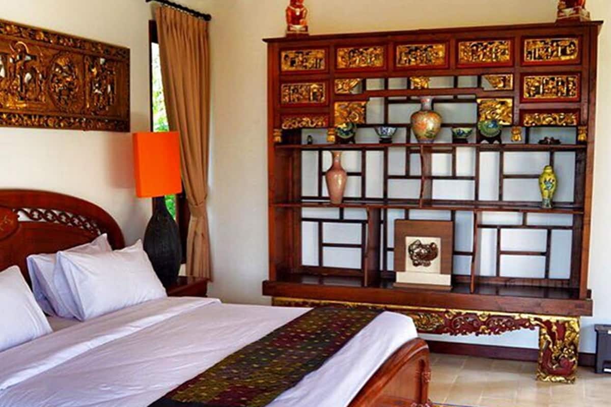 Un dormitorio con una cama, una mesita de noche, un mueble decorativo y un suelo estampado.
