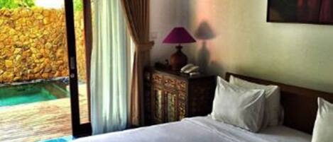 A hotel room with a bed, a lamp, a painting, and a view of a pool.
