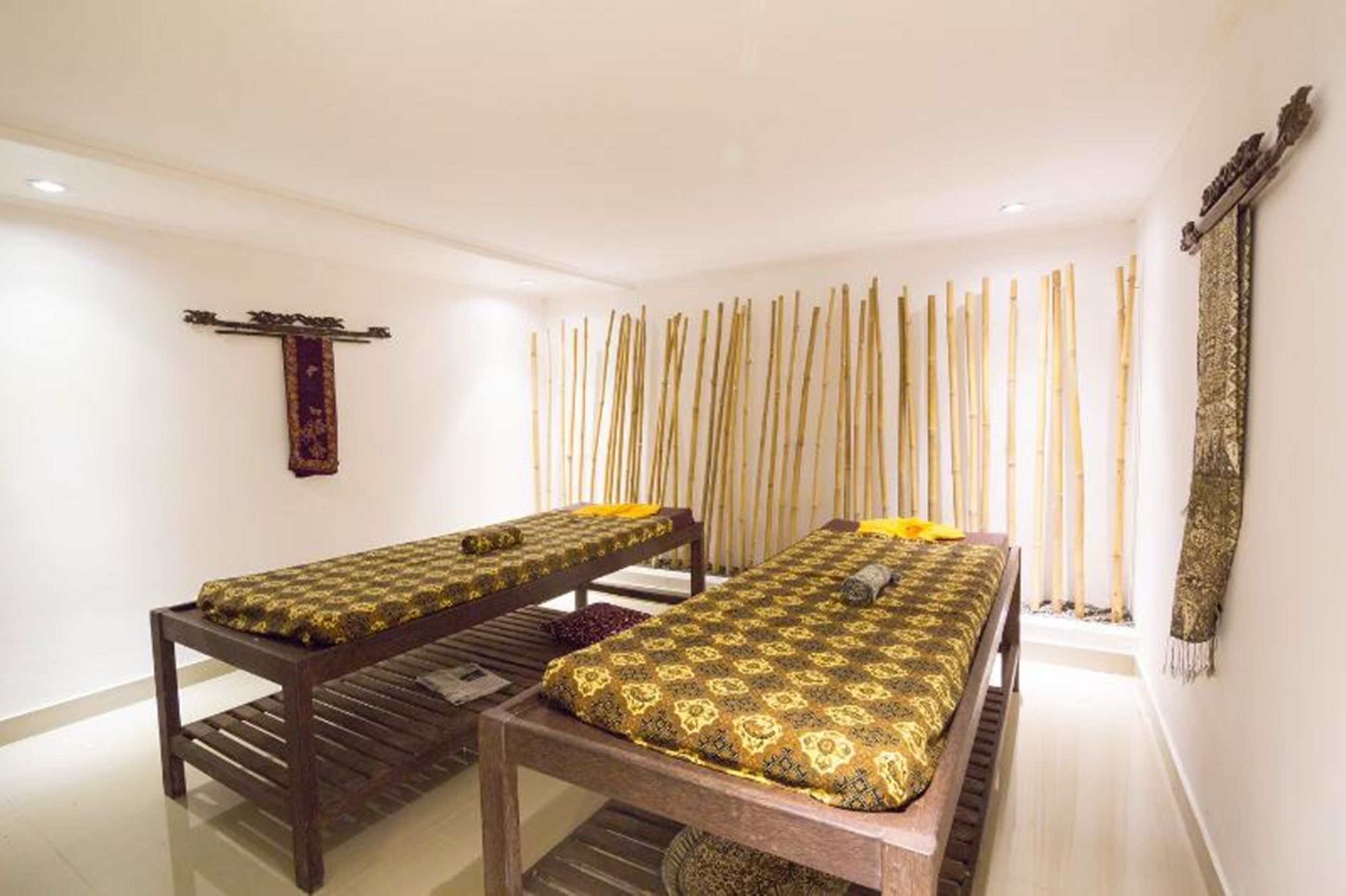 A room with two wooden beds, a wall-mounted decorative item, and a bamboo curtain.