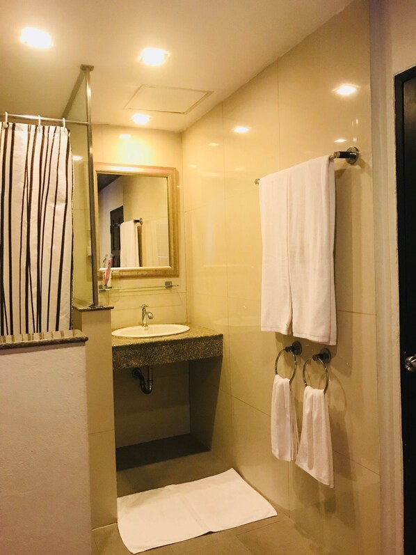 Un baño con lavamanos, espejo, toallero y cortina de ducha.