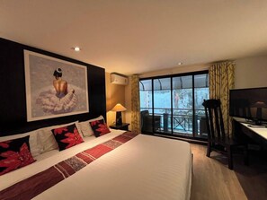 Quarto de hotel com uma cama grande, uma televisão, uma mesa de trabalho e uma janela com vista.