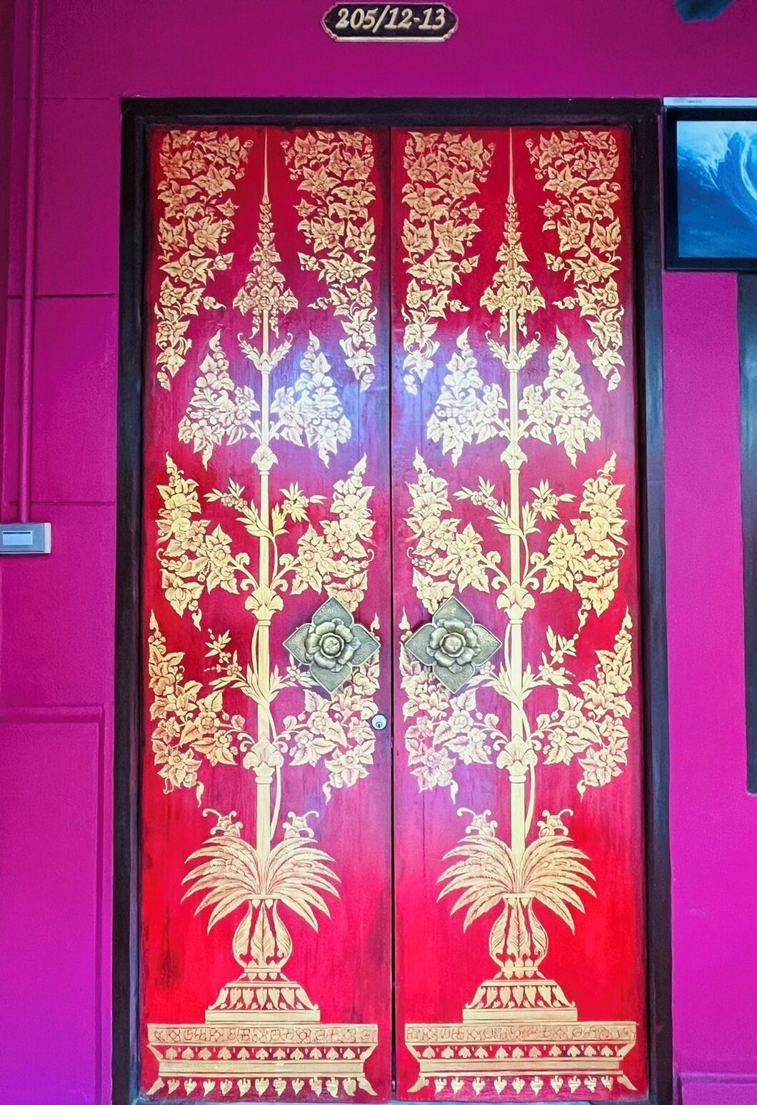 A door with intricate golden floral patterns and a number plate above it.