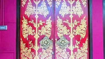 A door with intricate golden floral patterns and a number plate above it.