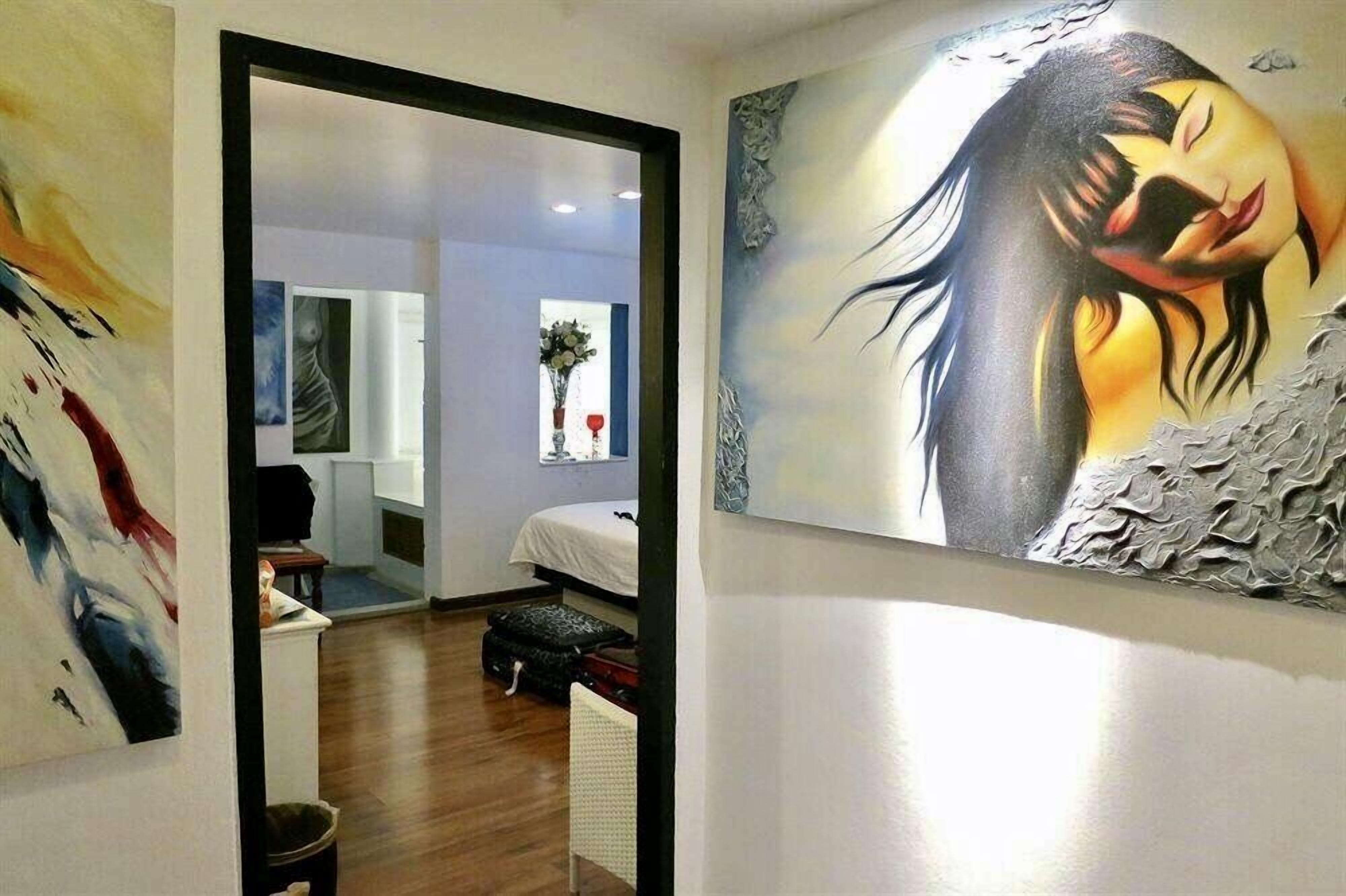 A room with a bed, a small table, and a painting on the wall.