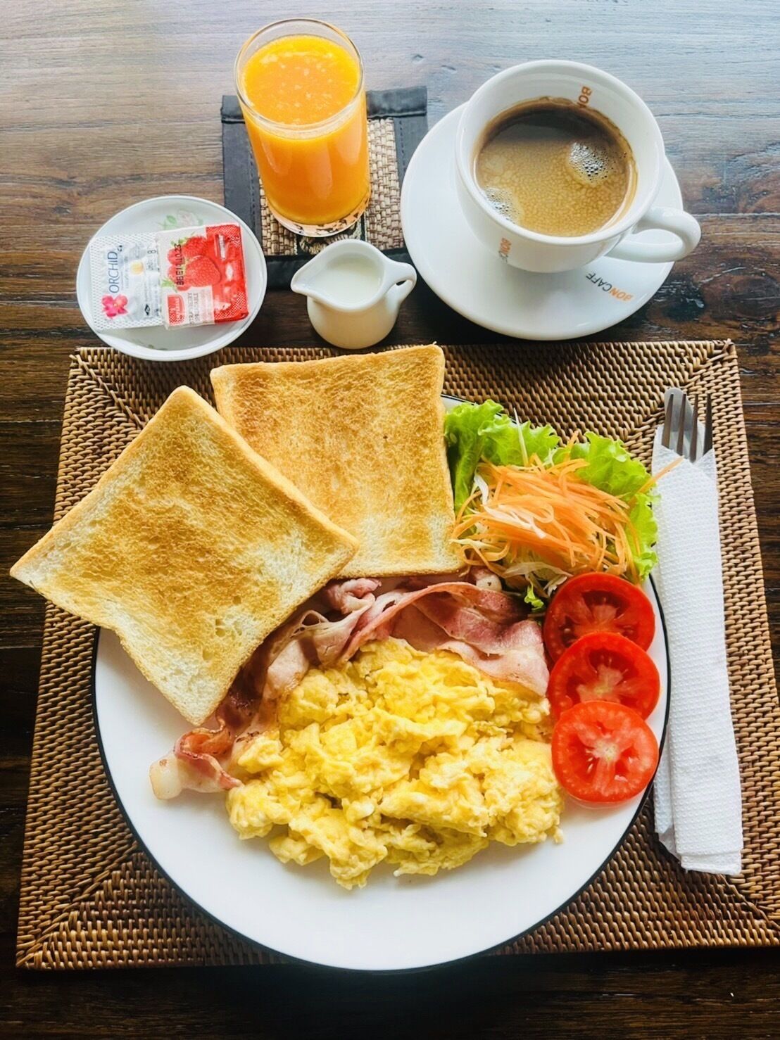 A breakfast plate with toast, eggs, bacon, tomatoes, lettuce, and a cup of coffee.
