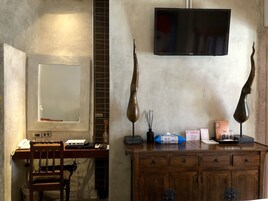 Une pièce comprenant un bureau en bois, une chaise, un téléviseur fixé au mur et un meuble avec des tiroirs.