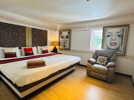 Una habitación de hotel con una cama grande, una silla, un cuadro y una ventana.