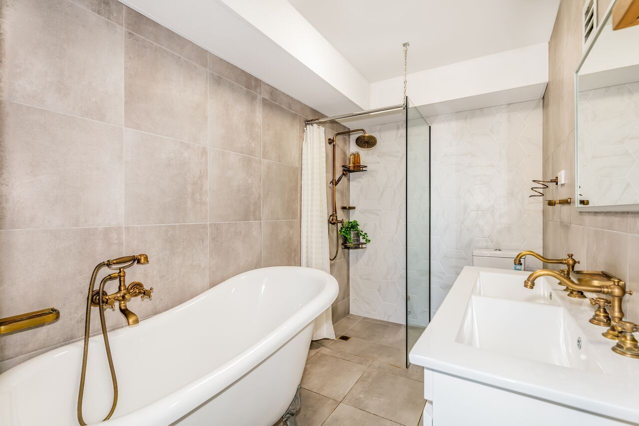 A modern bathroom with a freestanding bathtub, a glass-enclosed shower, and a vanity with a sink and mirror.