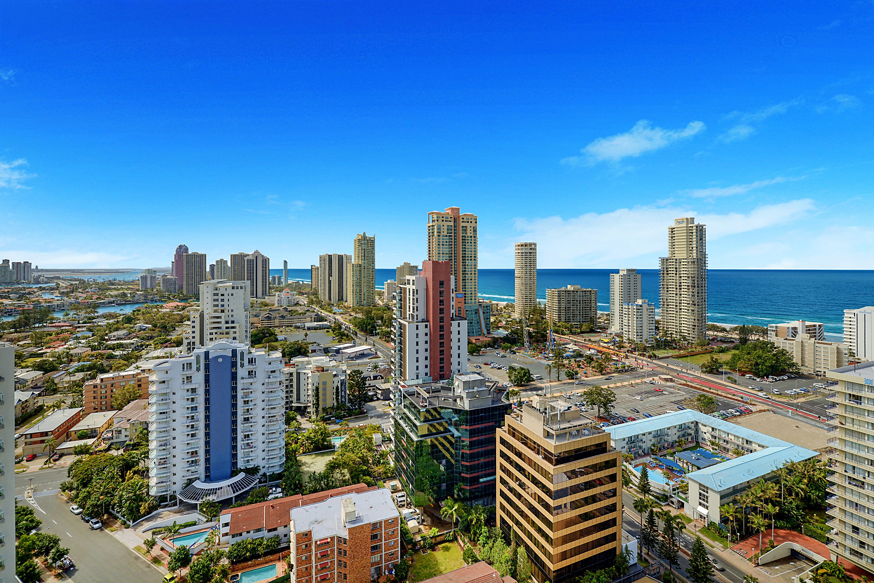 A high-rise hotel with multiple floors, a swimming pool, and a view of the ocean.