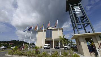 A building with multiple flags, a tower with a sign, and a parking lot.