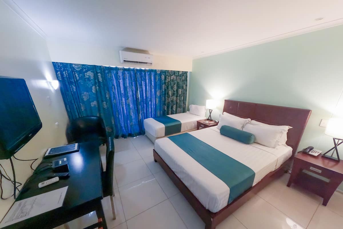 Een hotelkamer met twee bedden, een bureau met een computer, een televisie en een airconditioning.