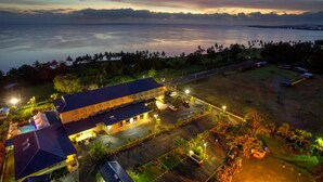 A coastal hotel with a large building, parking area, and a view of the sea.