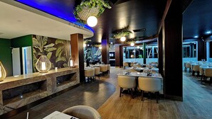 A restaurant with a modern interior, featuring a reception desk, dining tables, and chairs.