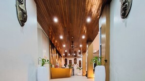 A reception area with a wooden ceiling, a reception desk, and a staircase leading to the upper floor.