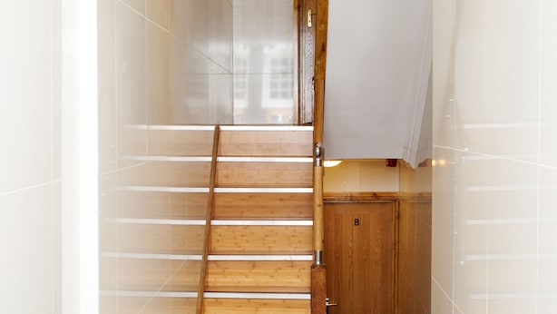 A modern interior with a wooden staircase, a tiled floor, and a wooden door labeled 'B'. - Beaconsfield Apartments (London)
