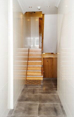 A modern interior with a wooden staircase, a tiled floor, and a wooden door labeled 'B'. - Beaconsfield Apartments (London)