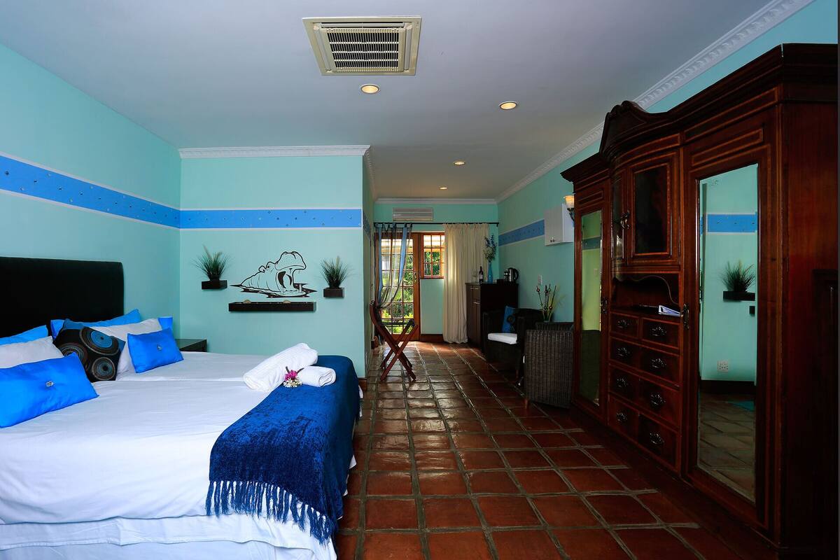 Une chambre d’hôtel avec un lit, une armoire en bois, une salle de bain avec douche et une vue sur l’extérieur.