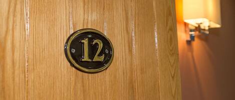A wooden door with a brass number plate displaying the number 12.