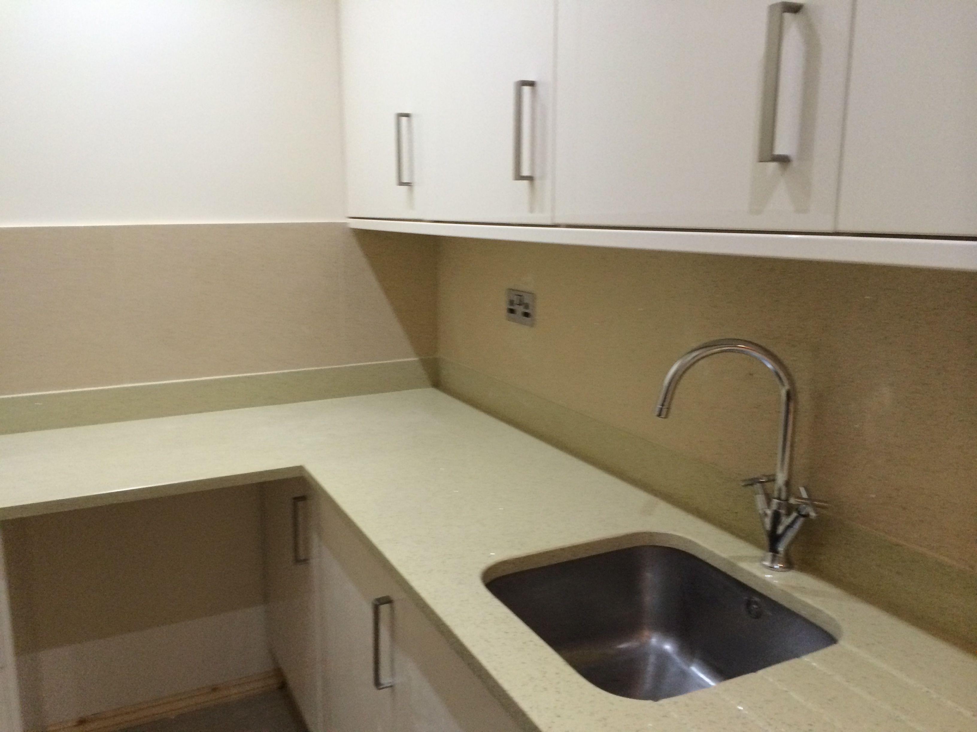 A kitchen with white cabinets, a stainless steel sink, and a countertop.