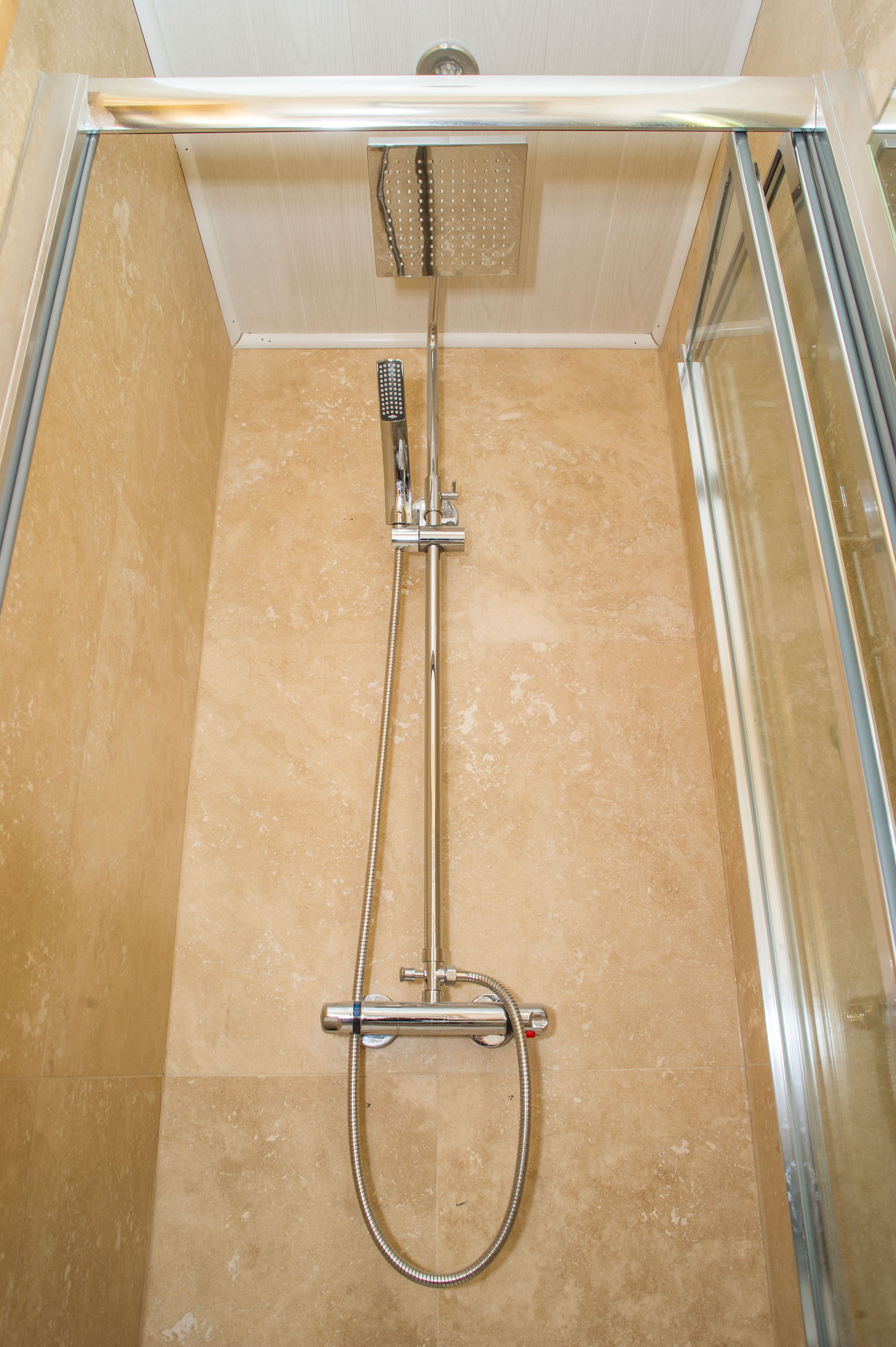 A shower with a handheld showerhead and a wall-mounted faucet.