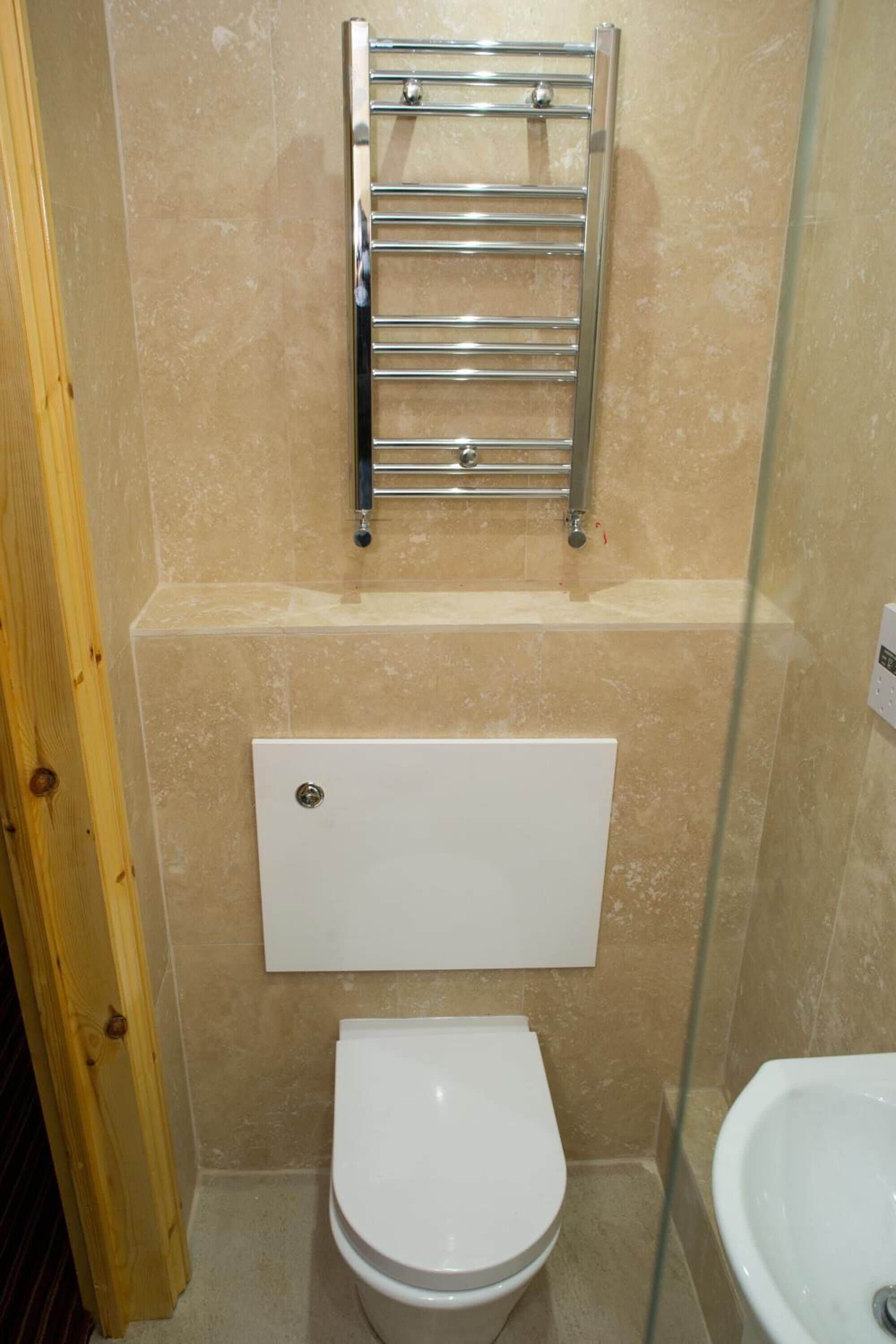 A bathroom with a white toilet, a glass shower enclosure, and a chrome towel rack.