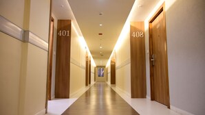 Un couloir d’hôtel avec les portes numérotées 401 et 408, un plancher en bois et un éclairage encastré.
