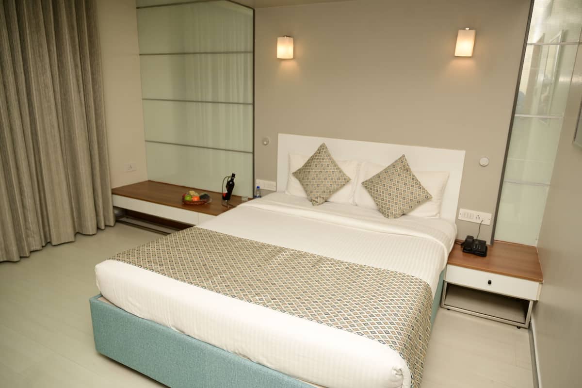 A hotel room with a bed, bedside table, nightstand, and a mirror.
