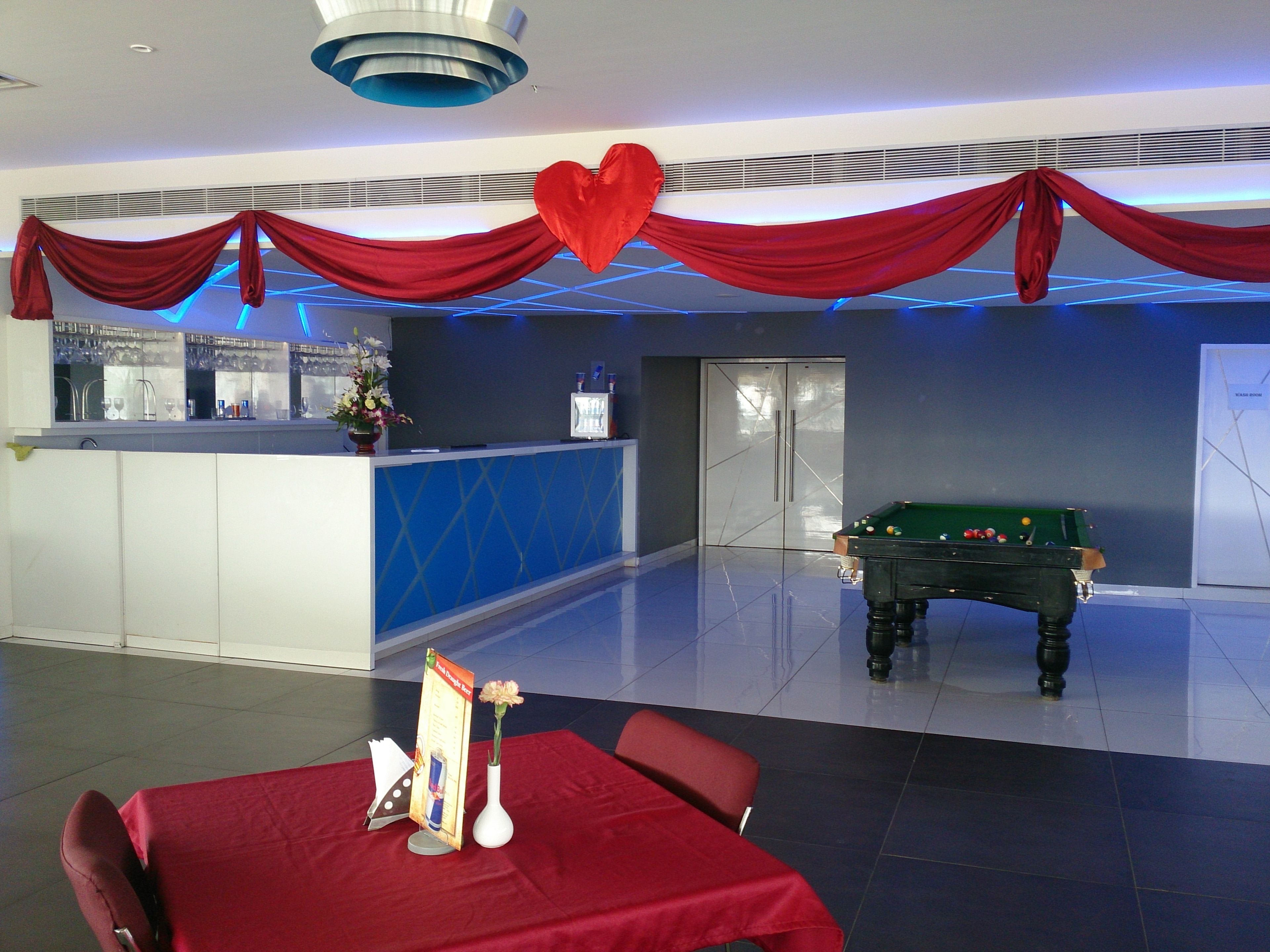 Zona reception con tavolo da biliardo, scrivania della reception e soffitto drappeggiato di rosso.