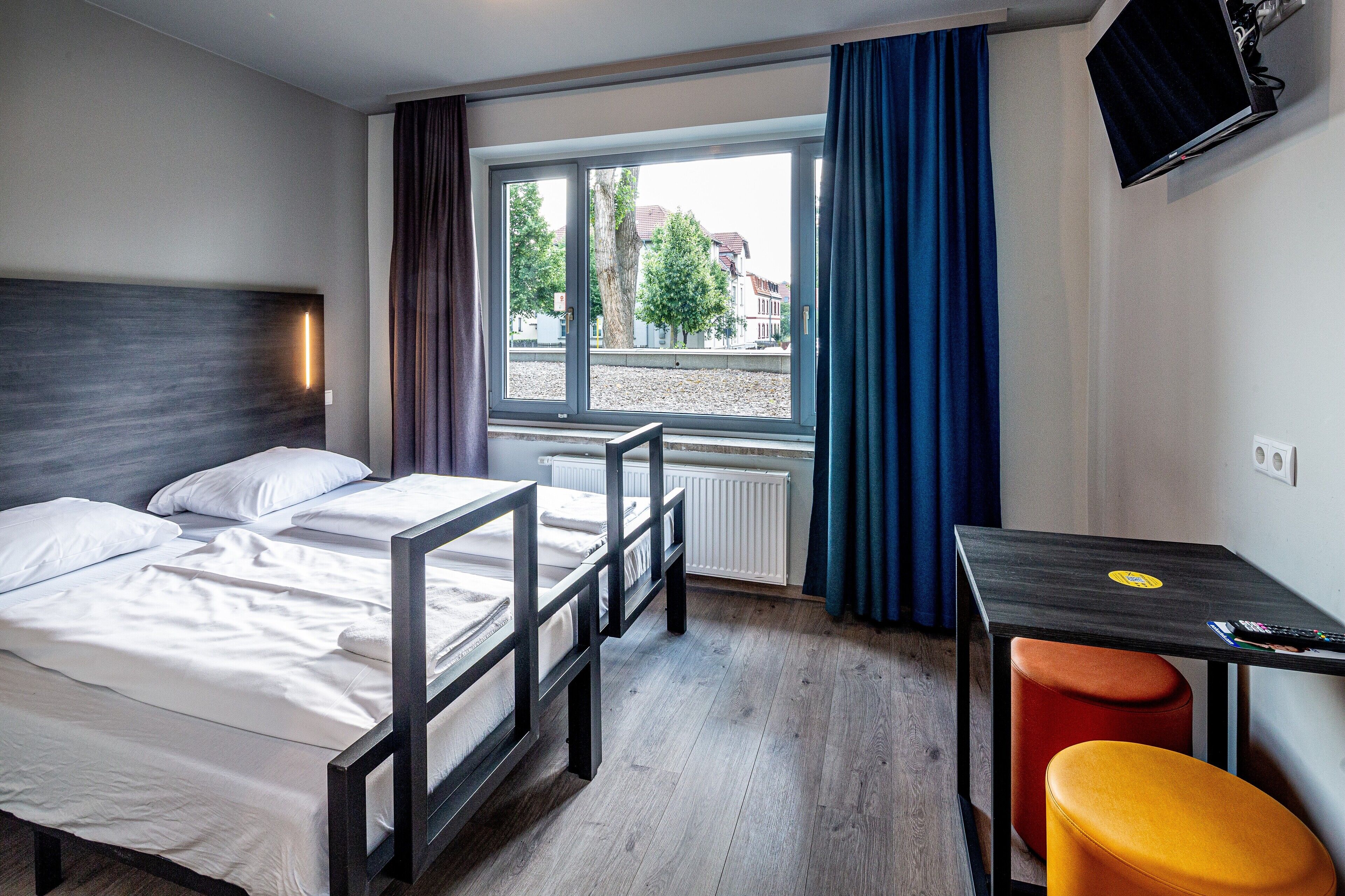 Een hotelkamer met een bed, een bureau, een stoel en een televisie aan de muur.