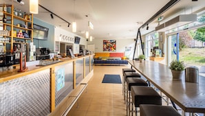 A modern bar area with a counter, seating, and a large window offering a view of the outdoors.